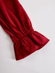 FJØRNA red velvet pleated ruffled long sleeve blouse with a feminine design and textured fabric.