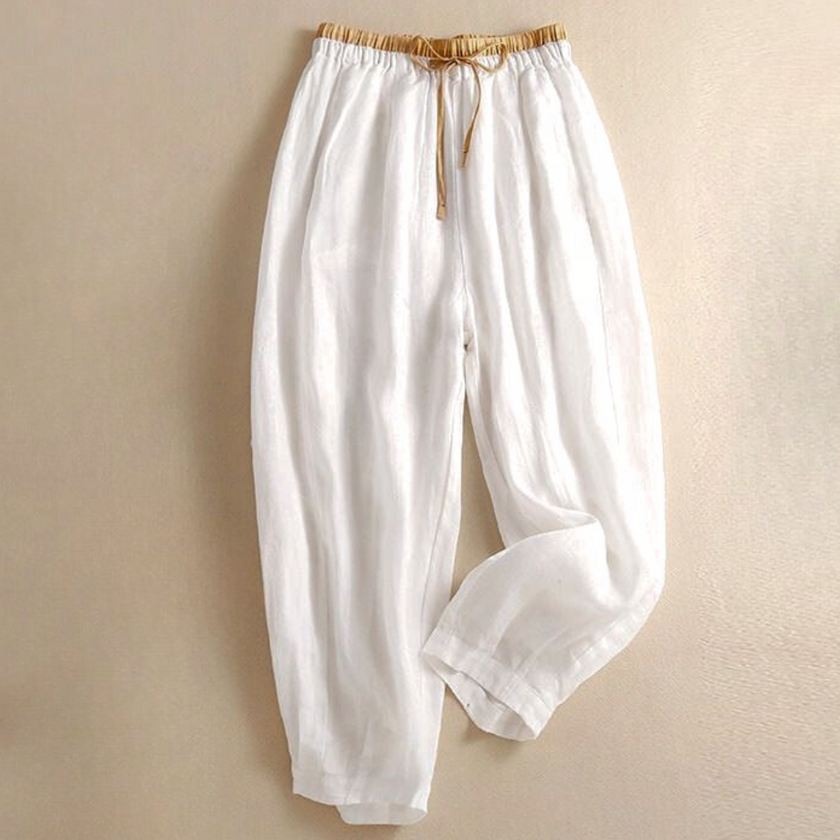 FJØRNA women's linen tapered trousers with a relaxed fit and cropped length, shown on a model standing in a neutral setting.