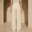 Women’s high waisted tailored wide leg trousers by FJØRNA, featuring a sleek fit and wide-leg design in neutral fabric