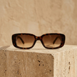 FJØRNA retro rectangular unisex sunglasses with black frames and dark tinted lenses, stylish accessory for women and men.