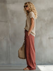 FJØRNA brick red cotton linen wide-leg women's trousers displayed on a model, showcasing relaxed fit and casual style.