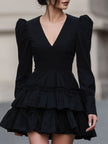 FJØRNA black leather mini dress with puff sleeves and tiered design, stylish and dramatic for evening wear or special occasions.