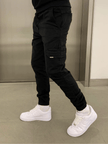 FJØRNA black cargo jogger trousers with multiple pockets and relaxed fit, made from comfortable fabric.