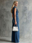 Blue washed denim sleeveless jumpsuit with collar for women by FJØRNA, shown hanging on a white background.