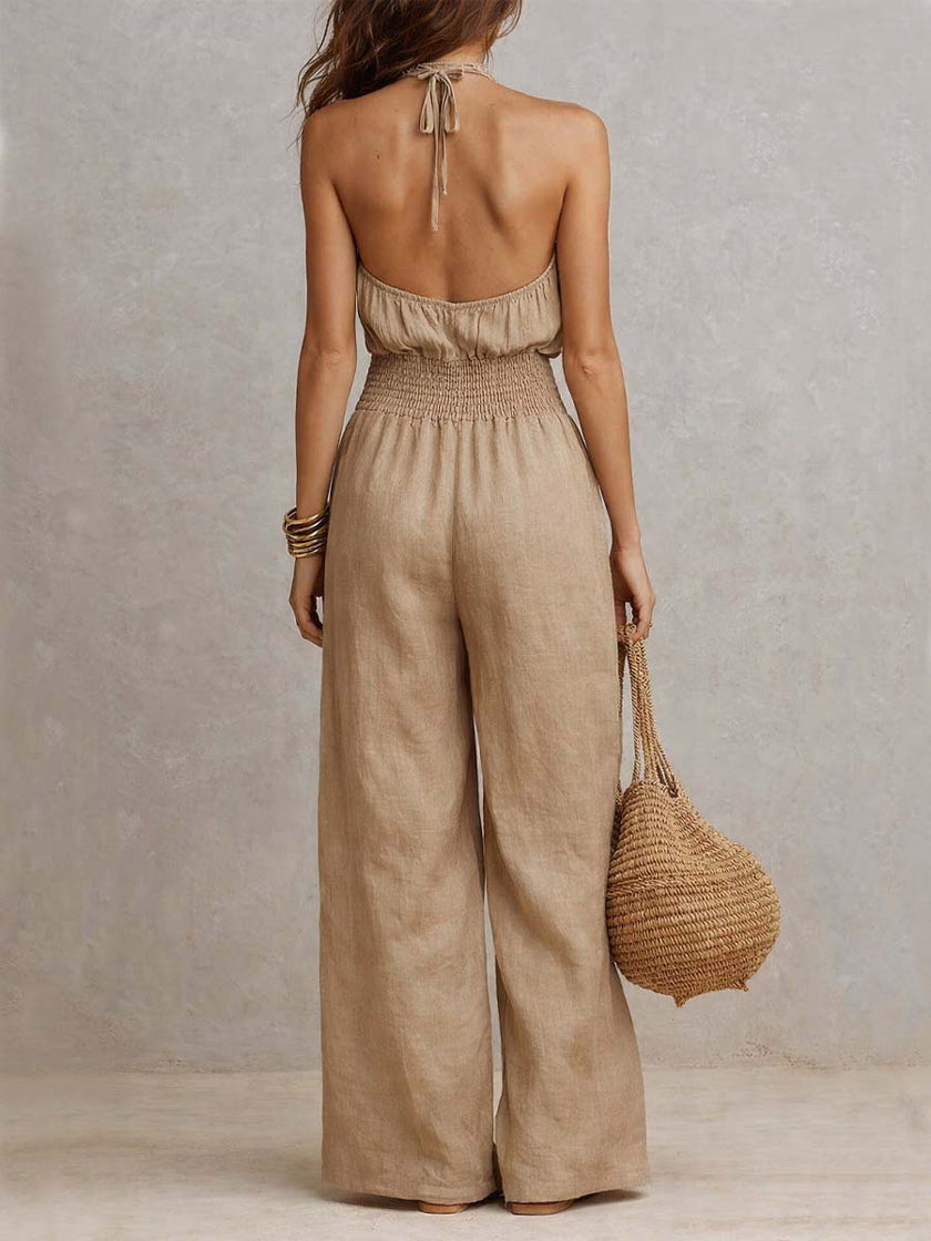FJØRNA tan cotton linen sleeveless jumpsuit with halter neck, smocked waist, and wide-leg design, perfect for summer wear.