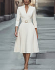 FJØRNA gold midi dress for women with V-neck, A-line silhouette, and three-quarter sleeves, showcased on a model.