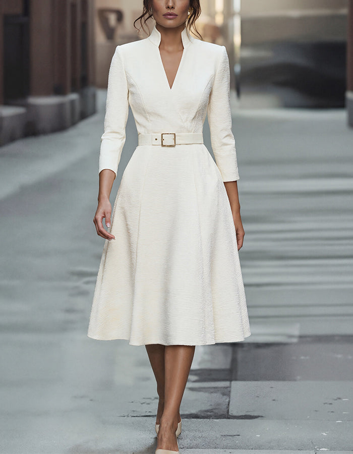 FJØRNA gold midi dress for women with V-neck, A-line silhouette, and three-quarter sleeves, showcased on a model.