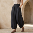 Women’s linen blend harem trousers with elastic waist, relaxed fit, by FJØRNA, shown in neutral color with flowing fabric.