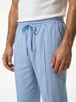 Close-up of FJØRNA men's linen trousers featuring relaxed fit and breathable fabric for comfortable summer wear.