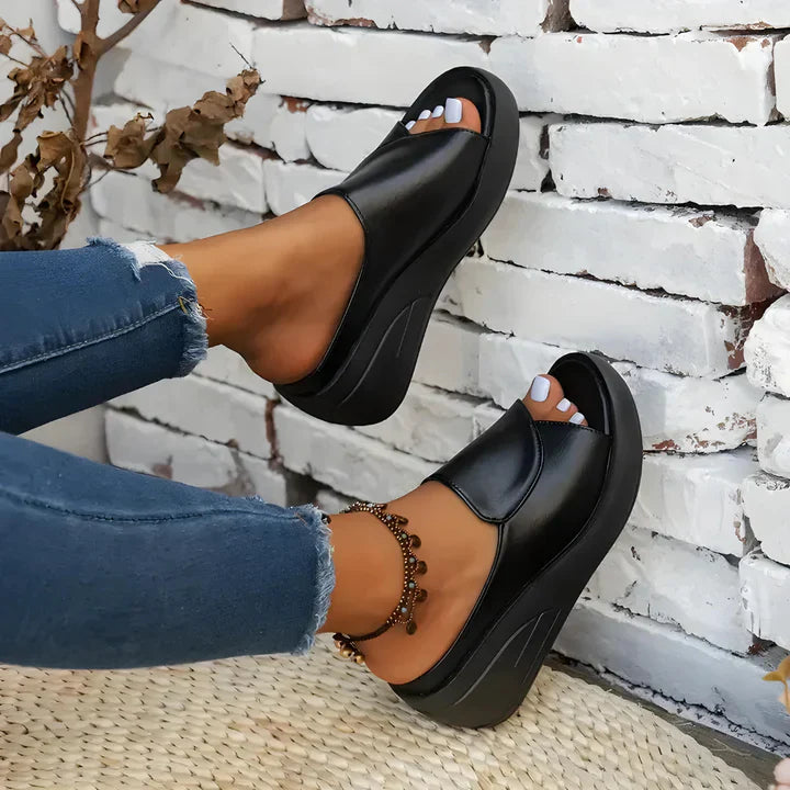 FJØRNA Eliza™ orthopedic slip-on wedge sandals with cushioned footbed and open-toe design, featuring neutral-toned straps.