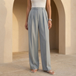 Women's high waisted pleated wide leg trousers by FJØRNA, shown in a stylish, flowing fabric with a relaxed fit.