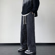 Black distressed trousers by FJØRNA featuring ripped details and a relaxed fit, styled on a model.