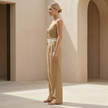 FJØRNA women’s pinstripe strapless wide-leg jumpsuit with fitted bodice and flowing pant legs, displayed on a hanger.