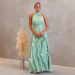 FJØRNA elegant women's maxi dress with halter neck and ruffle details, flowing fabric perfect for formal or summer occasions.
