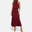 FJØRNA draped sleeveless halter maxi dress displayed on a hanger with flowing fabric and elegant design.