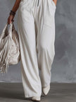 White faux suede western fringe V-neck jumpsuit by FJØRNA with fringe details and a stylish V-neck design.