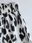 White leopard print chiffon wide-leg trousers for women by FJØRNA, featuring flowing fabric and relaxed fit.