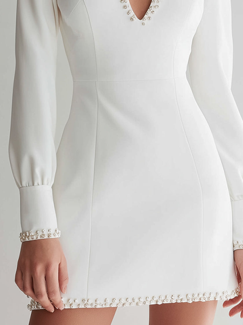 FJØRNA white long-sleeve mini dress with pearl-embellished keyhole neckline, stylish and elegant for evening wear.