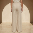 Women’s beige asymmetric waist trousers with metal buckle by FJØRNA, featuring stylish design and tailored fit.