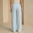 Women’s FJØRNA criss cross waist wide-leg trousers featuring a high waist, flowing fabric, and relaxed fit in neutral color.