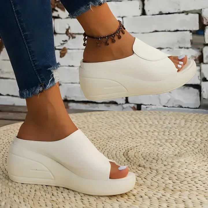 FJØRNA Eliza™ orthopedic slip-on wedge sandals with cushioned footbed and neutral beige color, shown from side view.