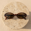 Retro oval sunglasses for women by FJØRNA, stylish unisex accessories with dark tinted lenses and a vintage-inspired frame.