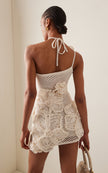 FJØRNA Kendria floral crochet mini dress on a hanger, showcasing intricate crochet details and vibrant floral pattern.