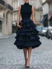 FJØRNA sleeveless high neck tiered ruffle midi dress with flowing fabric and layered ruffle details, perfect for elegant occasions.