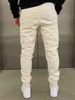 Cream cargo jogger trousers by FJØRNA with multiple pockets and a relaxed fit, shown flat on a white background.