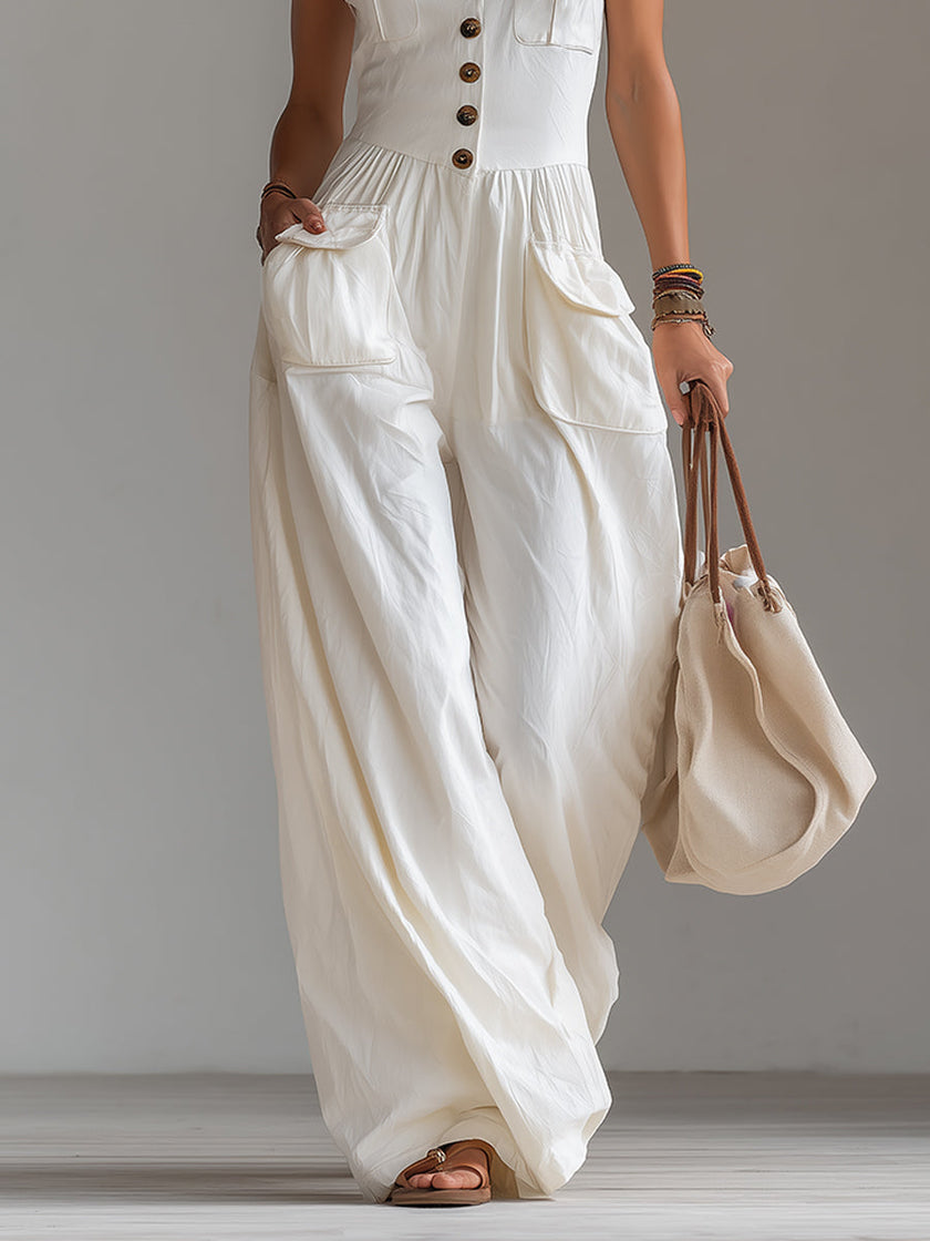 White sleeveless wide-leg jumpsuit by FJØRNA with patch pockets, shown on a model in a stylish, casual fashion setting.