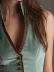 FJØRNA sage velvet slim-fit waistcoat with leather trim, styled as a tank top, featuring a sleek, tailored look with detailed accents.