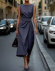FJØRNA women's midi dress with round neck, sleeveless design, and pleated fabric for a stylish, elegant look.