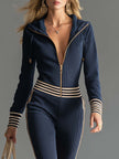 Dark blue knitted hooded zip-up jumpsuit by FJØRNA featuring a V-neck and cozy knit fabric, shown on a model.