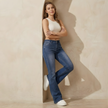 Women's mid waist stretch flared denim jeans by FJØRNA, shown styled with a casual top and paired with neutral footwear.