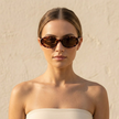 FJØRNA retro oval sunglasses for women, stylish unisex accessory with dark tinted lenses and sleek frame.