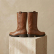 FJØRNA women's leather boots showing ankle-high design with smooth black leather and stylish stitching details.
