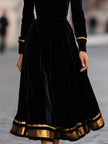 FJØRNA elegant velvet midi dress with gold trim, featuring a fitted silhouette and stylish design, shown in a close-up image.