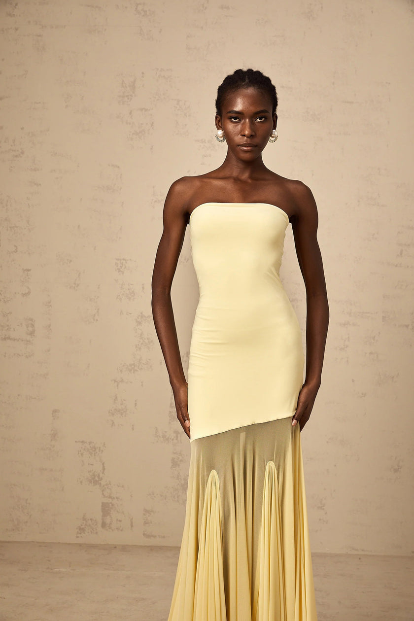 FJØRNA Josiane yellow off-shoulder sheer tulle maxi dress displayed on a hanger with flowing fabric and elegant design.