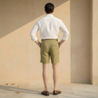 Men's high waist linen shorts by FJØRNA with pleats, showcasing lightweight, breathable fabric and a relaxed fit.