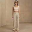 FJØRNA wide leg high waist pleated women's pants displayed on a model, showcasing the relaxed fit and stylish design.