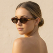 FJØRNA retro oval sunglasses for women, unisex accessories with dark tinted lenses and smooth black frames.