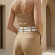 Women’s pinstripe strapless wide-leg jumpsuit by FJØRNA, featuring a fitted strapless top and flowing wide-leg pants.