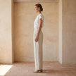 FJØRNA women's linen wide-leg trousers with high waist, tailored fit, and relaxed leg design, shown in natural fabric texture.
