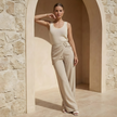 Women’s beige asymmetric waist trousers with metal buckle, stylish FJØRNA pants featuring a modern design and tailored fit.