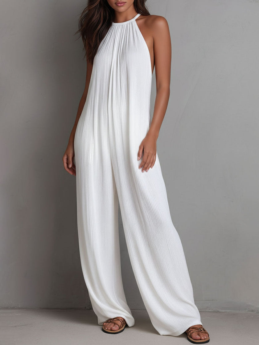 White pleated halter neck wide-leg resort jumpsuit by FJØRNA, featuring a stylish halter top and flowing wide-leg pants.