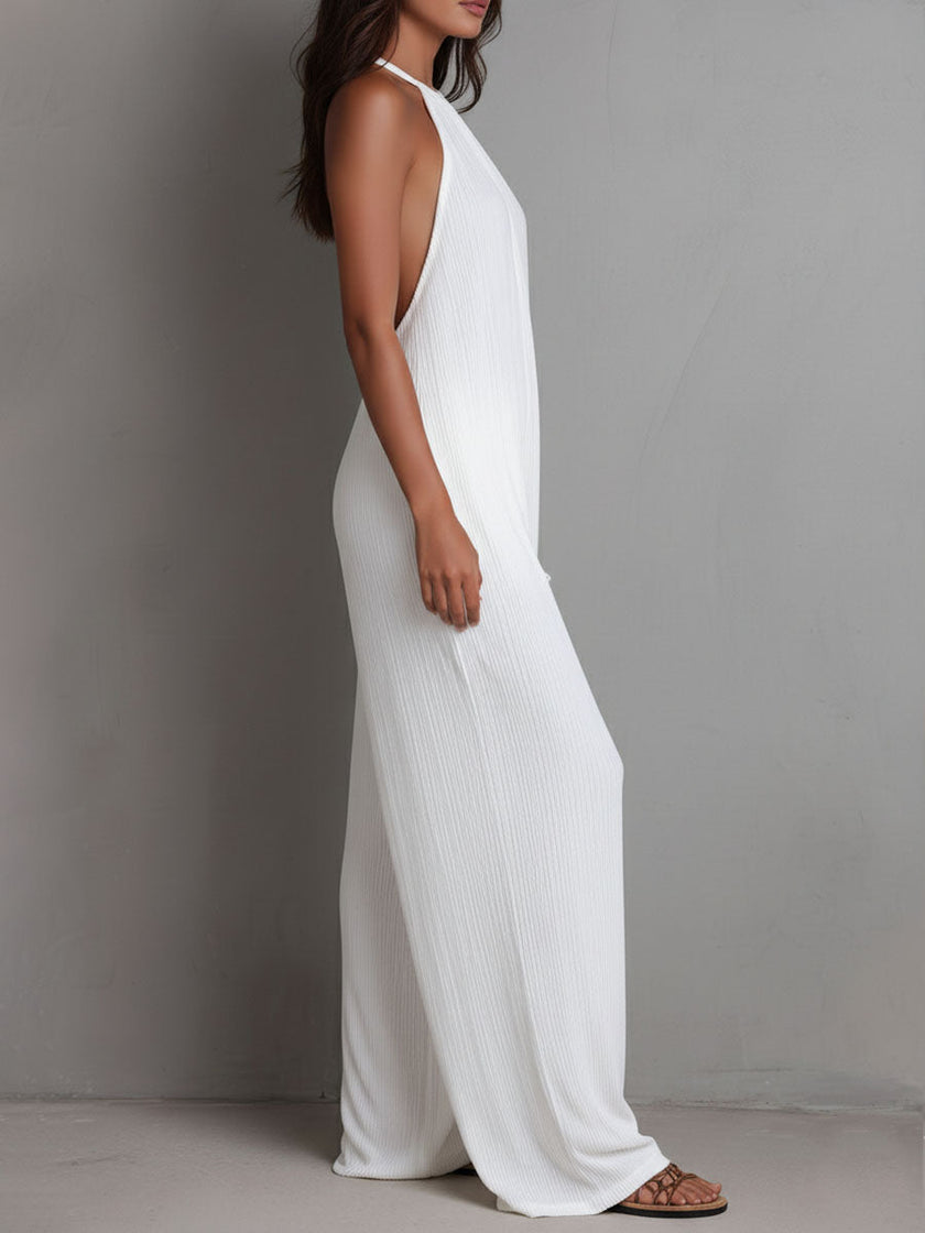 White pleated halter neck wide-leg resort jumpsuit by FJØRNA, featuring flowing fabric and stylish design, displayed on a mannequin.