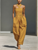 FJØRNA mustard linen-blend women's jumpsuit with crisscross neckline and relaxed wide-leg pants, shown on a model.