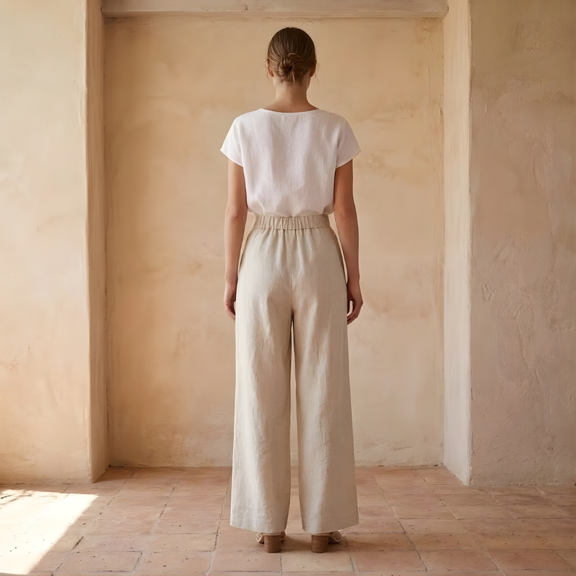 FJØRNA women's linen wide-leg trousers with high waist and tailored fit, shown in natural beige fabric.