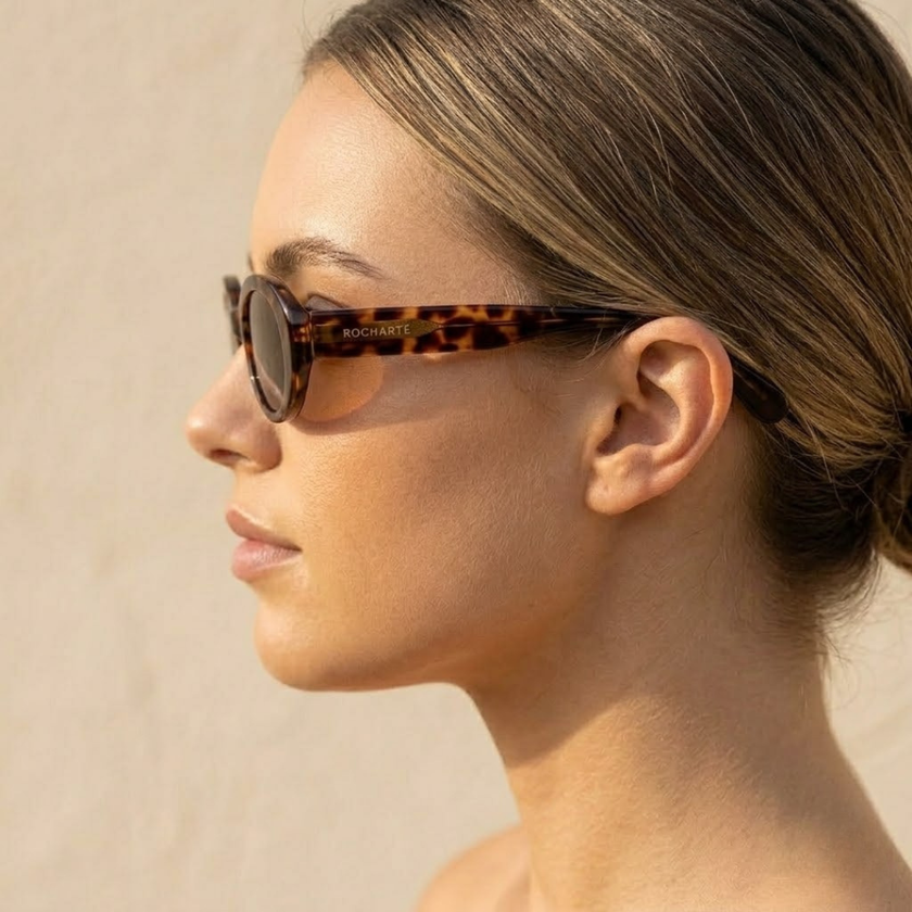 FJØRNA retro oval sunglasses for women, unisex accessories with black frames and dark tinted lenses, stylish and vintage-inspired.