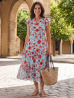 FJØRNA women's floral tiered summer midi dress hanging on a rack, showcasing lightweight fabric and vibrant floral pattern.